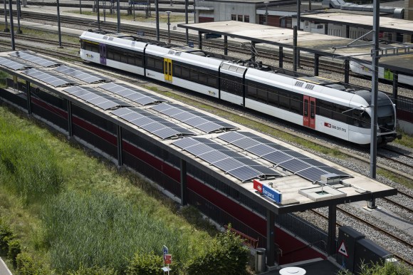Un treno svizzero passa accanto a un installazione di pannelli solari