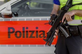 Un poliziotto armato di mitra davanti a un autopattuglia della polizia cantonale ticinese.