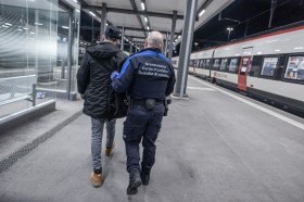 guardia di confine accompagna un uomo su un binario di una stazione