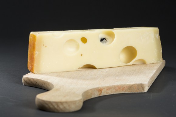 formaggio coi buchi su un tagliere di legno