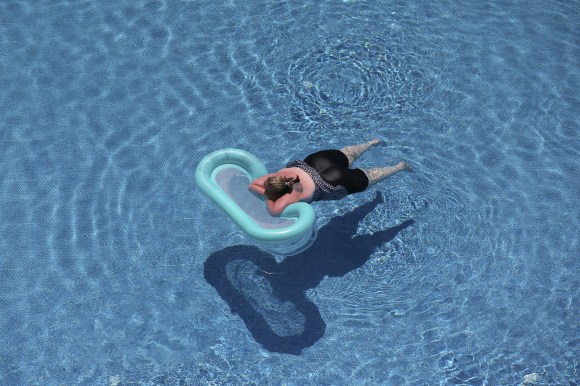 donna in piscina, appoggiata su materassino fotografata dall alto