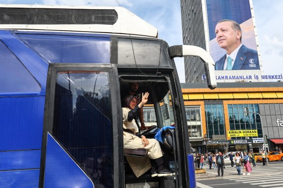 autobus con una donna e in secondo piano edificio con gigantografia di Erdogan