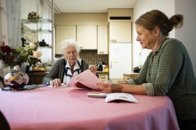 Foto di una donna che mostra dei documenti a un anziana su un tavolo