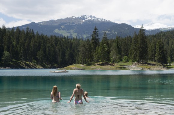 Tre giovani donne fanno il bagno in un laghetto di montagna in Svizzera.