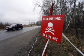 Un auto passa davanti a un segnale di pericolo per le mine in Ucraina