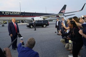 Donald Trump parla ad un gruppo di giornalisti davanti al suo jet privato.