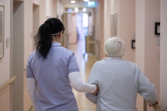 fotografati di spalle un infermiera tiene sotto il braccio un(a) paziente anziano/a