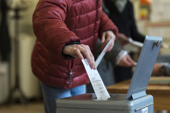 una persona infila la scheda elettorale nell urna
